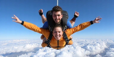 Two people doing a tandem skydive high above the clouds